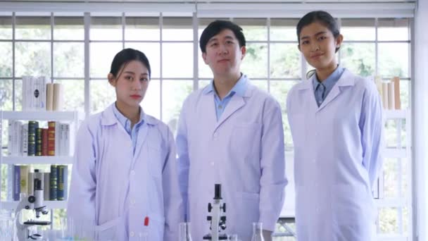 Portrait of successful team of male and female Asian medical researcher and scientist working in medical lab wearing labcoat looking at camera. — Stock Video