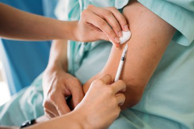 Doktor elleri hastaya aşı yapıyor.