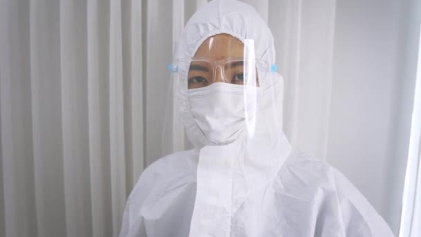Ritratto del giovane medico asiatico in uniforme del kit PPE con guanti a mano che indossano ppe generale durante l'epidemia di covid-19 mentre si prepara a trattare i pazienti con sintomi - 4k 60fps footage. — Video Stock