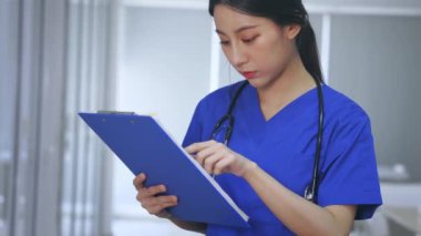 Genç bayan doktor hastanede raporları kontrol ediyor.