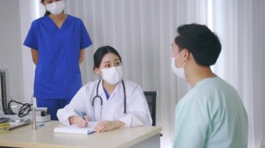 Doktor maske takan bir hastayla konuşuyor.