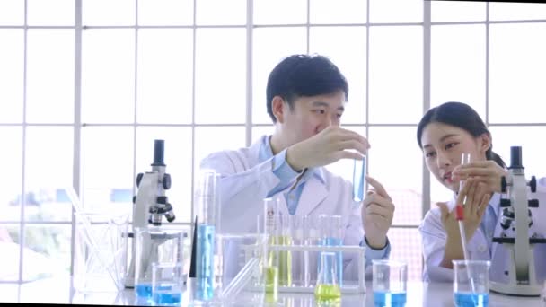 Squadra di giovani scienziati asiatici di sesso femminile e maschile che utilizzano il microscopio e tengono una provetta nel laboratorio di ricerca sulle scienze biologiche — Video Stock