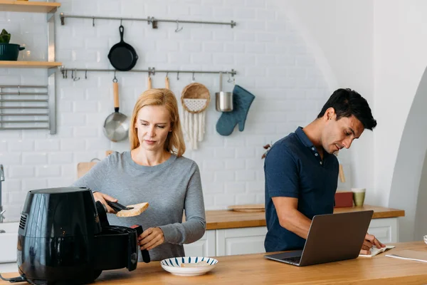 Kadın, uçak fritözüyle çalışıyor ve adam dizüstü bilgisayar kullanıyor.