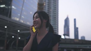 Mutlu kadın telefonda yürüyüp konuşuyor.