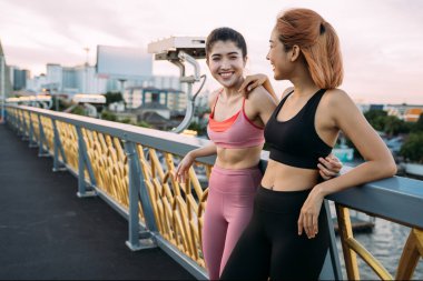 Genç bayan sporcular köprüde dikilip konuşuyor.