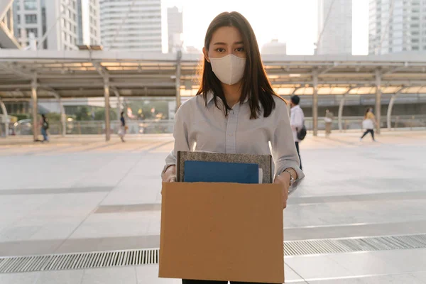 Mulher com máscara disparada de trabalho segurando caixa de itens — Fotografia de Stock