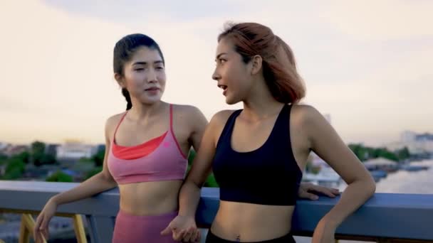 Jóvenes atletas femeninas de pie en el puente hablando — Vídeos de Stock