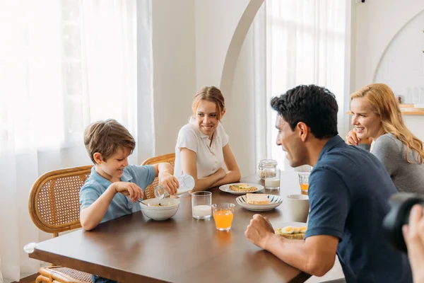 Family looking at boy pouring milk in cereals — Stock Photo, Image