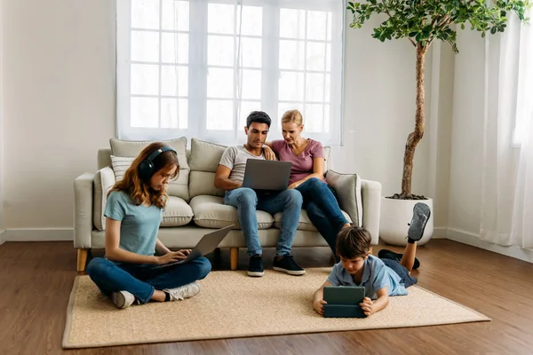 Familia sentados juntos usando dispositivo electrónico —  Fotos de Stock