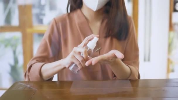 Mujer con máscara de aplicación de desinfectante en la cafetería — Vídeos de Stock
