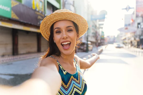 Young brunette woman using a mobile phone takes a self video selfie with attractive smile. — Stock Photo, Image