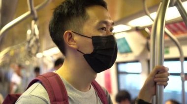 Coronavirus Covid-19 zatürree salgını sırasında metroda siyah cerrahi maske takan genç bir Asyalı 'yı ve 2,5 numaralı hava kirliliği krizini yakından izleyin.