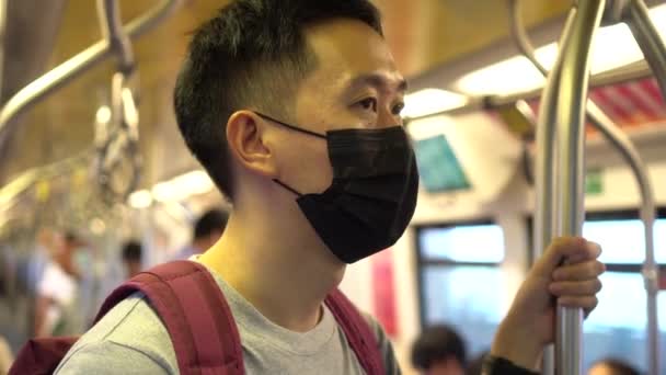 Primer plano de un joven asiático que llevaba una máscara facial quirúrgica negra en el tren subterráneo durante el nuevo brote de neumonía tipo Coronavirus Covid-19 y la crisis de contaminación atmosférica por smog pm 2.5 en la gran ciudad — Vídeo de stock