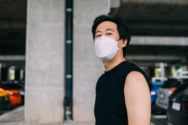 Aşılanmış genç adam Covid-19 aşısı olduktan sonra kollarını yapıştırıcı bandajla sargılıyor.