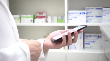 Pharmacist using mobile phone at drugstore room. Doctor touching a cell phone in medical concept