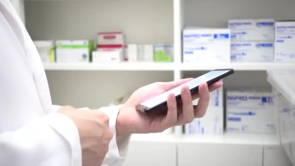 Pharmacist using mobile phone at drugstore room. Doctor touching a cell phone in medical concept — Stok video