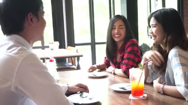 Four young Asian people, 1 man, 3 women, talking and smiling at cafe and restaurant — Stockvideo