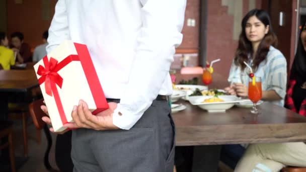 Young Asian couple giving present gift box and friends clapping hands nearby at restaurant — Vídeos de Stock