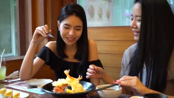 Two Asian female friends eating and having a meal together. Women enjoying good time at restaurant — Stockvideo