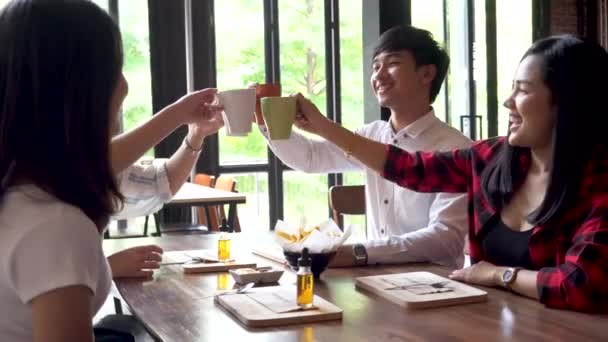Young business people raising cup of coffee together and say cheers on the table at the cafe — Stock Video