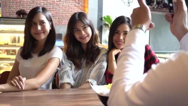 Friends group of Asian people, one male taking photos of three female friends at restaurant — Stockvideo