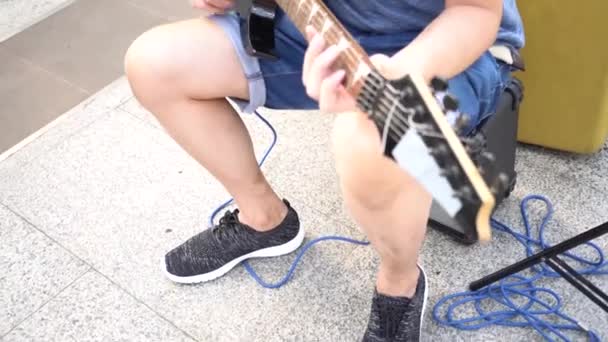 Street musician strumming guitar on the street outdoors while passerby walking by — Vídeo de Stock