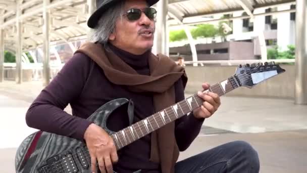 Close up shot of old street musician in sunglasses and hat strumming guitar on street outdoors — Vídeo de Stock