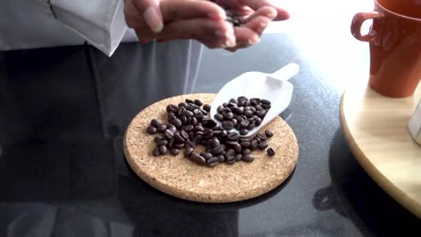 Young barista smelling coffee beans laying on table with smiley — Stok Video