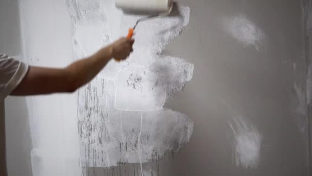 Young man worker painting wall with roller brush — Stock Video