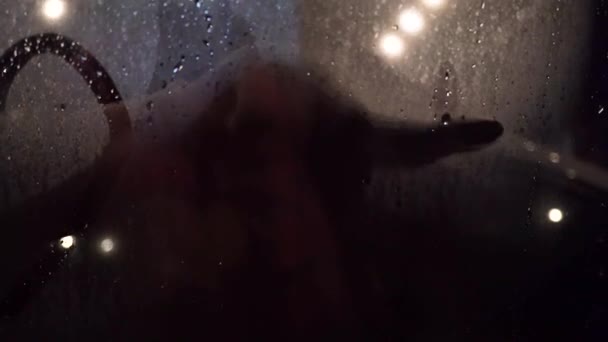 Person drawing smiley face with vapor steam on glass window — Stok Video