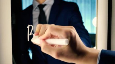 Smart business man writing the word Business on the mirror board