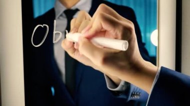 Smart business man writing the word Objective Mission on the mirror board