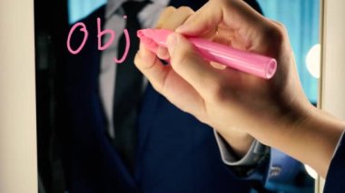Smart business man writing the word Objective Mission on the mirror board