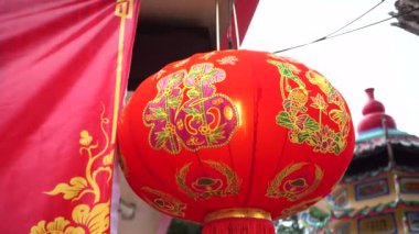 Chinese new years lantern inside a temple day time with the word written Happiness on the lantern