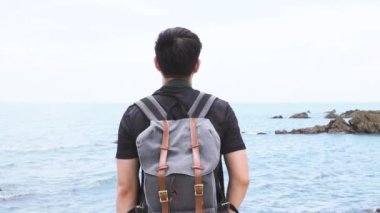 Back view of Young man spreading arms outstretched standing on the sandy beach