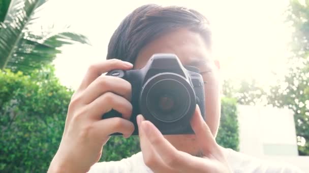 Young male photographer taking photos during sunset with back-lighting lens flare from behind — Video Stock