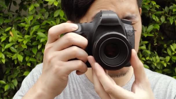 Close up of young male photographer taking photos in nature scenery — Stockvideo