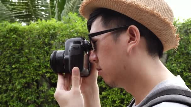 Rear side view of young male travel photographer tourist taking photos in nature scenery — Stockvideo