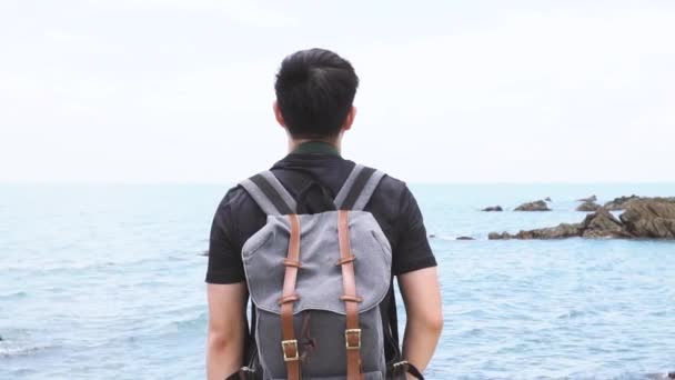 Back view of Young man spreading arms outstretched standing on the sandy beach — Vídeo de Stock