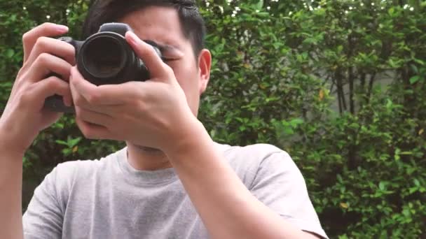 Orbit circle shot of young male photographer taking photos in nature scenery — Vídeos de Stock