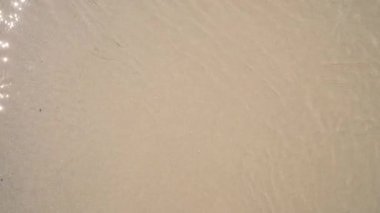 Kum ve deniz suyu dokusunun ve deseninin üst görüntüsünü kapatın. Fotokopi alanına sahip havadan soyut deniz dalgaları