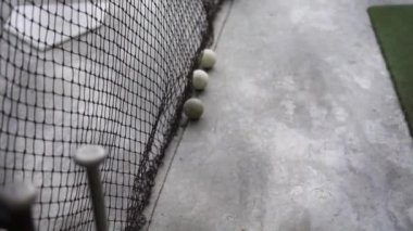 Beyzbol antrenmanı sahası ağdan beysbol sopası ve toplarıyla vuruyor.