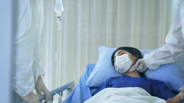 코로나 바이러스로 침대에 누워 있는 젊은 여성 환자를 마스크로 치료하는 페페 슈트를 입은 19 명의 의사들 — 비디오