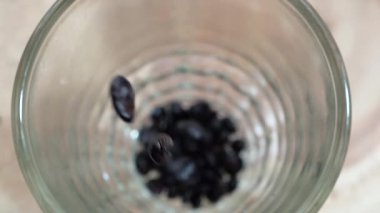 Temiz bardağın içine taze kavrulmuş aromatik kahve çekirdekleri dökülüyor.