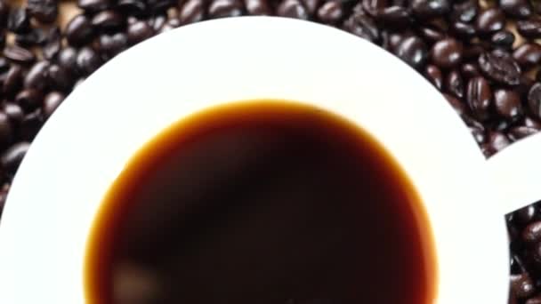 Cup of brewed espresso coffee on heap of dark coffee beans on wooden table — Stock Video