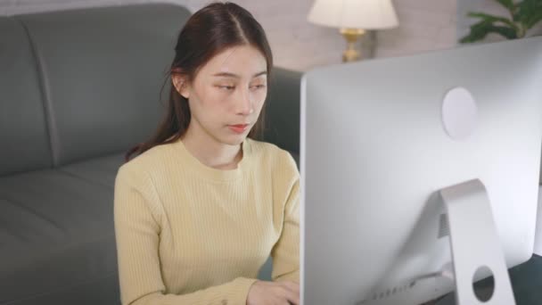 Young Asian businesswoman working from home and using desktop computer while sitting in living room — Stock Video