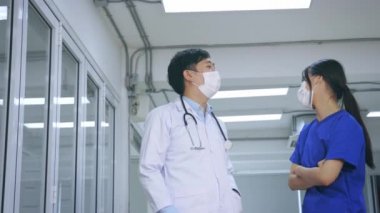 Steteskoplu ve maskeli genç Asyalı doktor ve hemşire beşlik çakıyor.