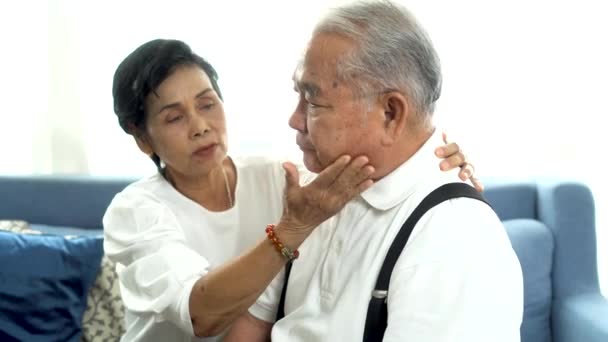 Nešťastný důchodce asijské senior pár sedět na pohovce, zatímco starší manželka utěšuje smutný manžel doma