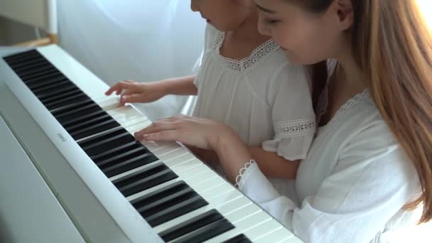 Mãe asiática ensinando filha para tocar teclado — Vídeo de Stock