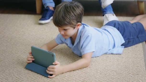 Niño acostado usando tableta digital — Vídeo de stock